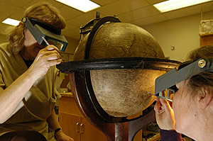 Conservators examining a globe. Click to enlarge.