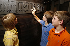 Three boys examining the Gutenberg Bible exhibit.