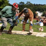 Molten Iron is carried in ladles by two founders clad in protective clothing.