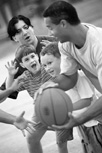 Photo of men and boys playing basketball.