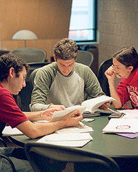 Three students studying at a library table