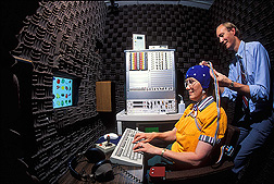 Photo: James Penland performs an electroencephalogram on a volunteer seated at a computer workstation. Link to photo information