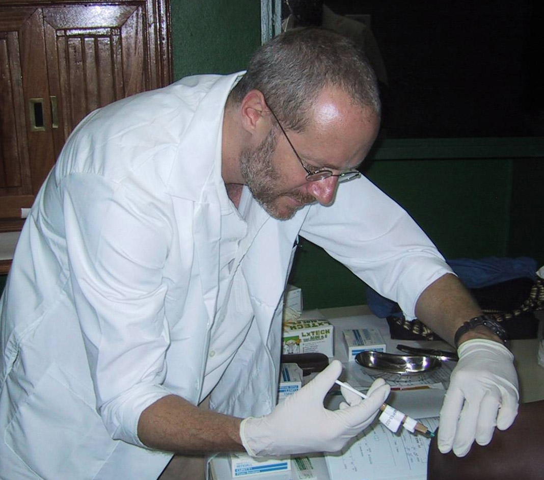 a researcher injects a malaria vaccine into a test tube.