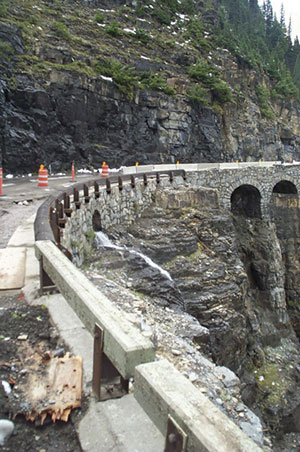 (Above) Most of the guard walls along the Going-to-the-Sun Road near Triple Arches were either sheared off or damaged by avalanches and rockslides. Some of the old guardrails are visible in the foreground. As part of the restoration of the road, a new generation of removable steel-backed guardrails, seen in the background, are installed prior to the spring road opening and removed when the road closes in the fall so avalanches can travel over the road without causing damage. Photo: NPS.