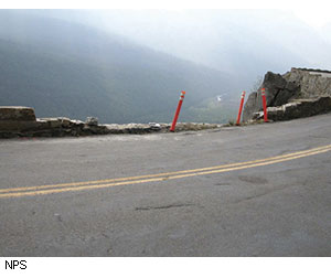 The three orange safety markers demarcated a section of guard wall that has been sheared off by repeated vehicle impacts. This guard wall will be reconstructed with new and stronger footings and historically compatible stone.