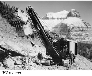 A crew uses a power shovel east of Logan Pass in 1932. Going-to-the-Sun Mountain, for which the road is named, is seen in the background.