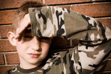 A photo of a young boy shielding his eyes from a bright light.