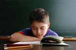 Boy sitting at a desk with an open book reading