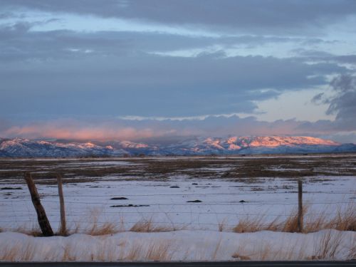 Winter sunrise from the valley floor north with snow in the foreground and pink mountains in the background.