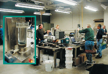 Photo: The air void analyzer (inset), which assesses the distribution of air voids in fresh concrete, is one of many innovations that could become more widely used under a revamped business plan. Here, participants in an inter-laboratory study set up air void analyzers in preparation for running tests.