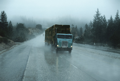 Foul weather like the rain that this truck is driving through calls for traffic countermeasures, such as variable message signs that reduce speed limits on slick roads.