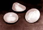 three breast implants consisting of a round, rubber silicone envelope filled with silicone gel.