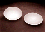 two breast implants consisting of a round, rubber envelope filled with saline (salt water).