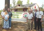 Debra Adkins stands with Webster Habitat Executive Director Charlie Park, (left) Reverend John Downs and other Habitat partners in front of the 