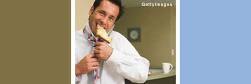 Photo showing a man eating a piece of toast while dressing for work.