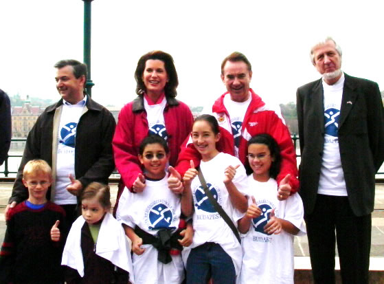 Secretary Thompson takes a break with children and families after taking a power walk through Budapest, Hungary, in observance of Child Health Day.  Pictured with the Secretary are (l. to r.) Mihaly Kokeny, U.S. Ambassador to Hungary Nancy Brinker, Secretary Thompson, and Gaza Jeszensky