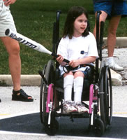 Photo of a young girl in a wheelchair, at bat in a game of softball.