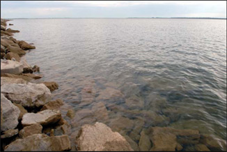 Photo of Lake Sakakawea near the shoreline. The rocks on the bottom of the lake can be seen through the clear water.