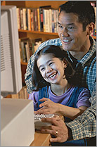 Photo of a man sitting at a computer with his daughter.