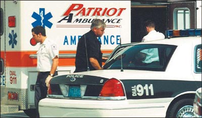 Photograph of police officer and EMTs in front of an ambulance