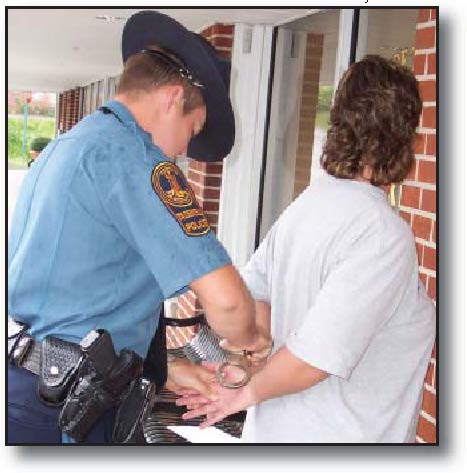 Photograph: Police officer handcuffing a woman outside the front door of a home