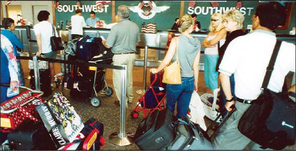 Travelers waiting in line to check baggage at an airline counter