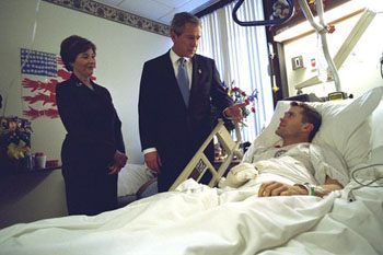 Picture of the George and Laura Bush at the bed side of an injured soldier.