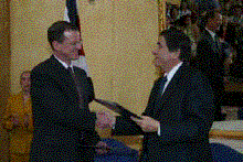 Charge d'Affaires Douglas M. Barnes and Costa Rican Foreign Minister Roberto Tovar exchange signed agreements.