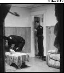 Photograph of two police officers searching a room