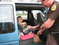 photo of an officer making sure that a child is in her car seat