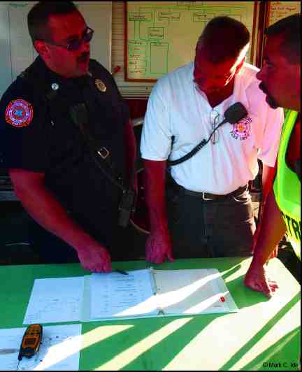 Photograph of members of fire department and EMT Squad discussing a plan