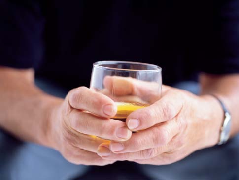 Photograph of hands holding a glass of alcohol