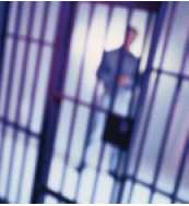 Photograph of prison guard standing outside of jail cell