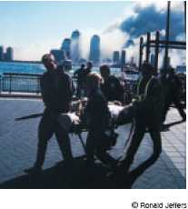 Photograph of New York Police Department and F D N Y members carrying a victim on 9/11/2001