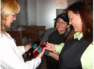 Crystal Collier, Executive Director of the Seldovia Village Tribe, shows Commissioner Stamps and PJ Bell, Alaska Training and Technical Assistance Provider, the new product line of blueberry and salmonberry vinaigrette.