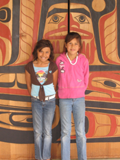 Two Port Gamble S'Klallam youth who have benefited from the Tribe's ANA foster care certification project standing in front of their Tribal longhouse.