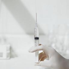 Photograph of a gloved hand holding a syringe