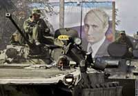 A Russian tank passes a billboard of Vladimir Putin
