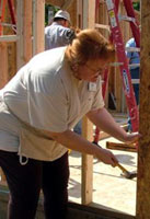 Photo of Karen Lee as she helps secure the plywood sheathing to the front of her future home