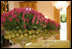 Hot pink tulips and green pears stand in line on the center table of the East Room.