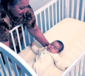 Image of an infant girl being positioned to sleep on her back.