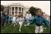 President Clinton and First Lady Hillary Clinton watch children's egg roll races during the 1993 Easter Egg Roll. Mrs. Clinton expanded the egg roll to the Ellipse to include additional activities for both children and adult attendees.