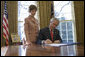 Laura Bush stands by President George W. Bush as he signs S. 843, the Combating Autism Act of 2006, in the Oval Office Tuesday, Dec. 19, 2006. White House photo by Eric Draper