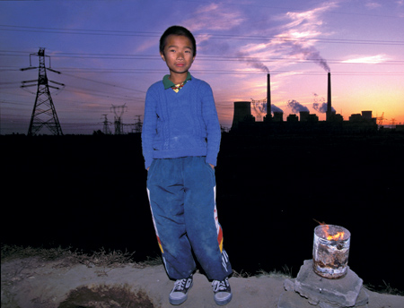 young boy standing in front of coal burning factories