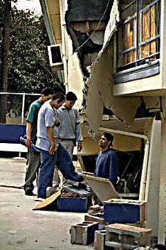 Photo of people looking at damage to a building left by an earthquake.