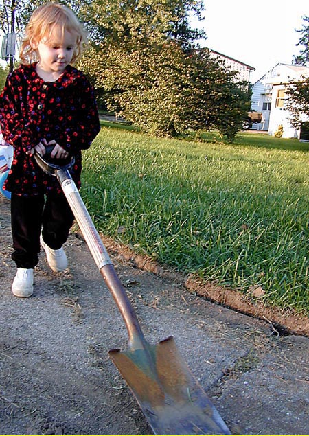 Photo of a child carrying a shovel.