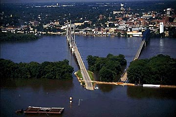 Aerial photo of a bridge almost submerged in flood waters.