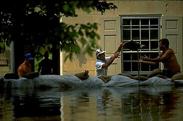 Photo of a person behind sandbags holding flood waters.