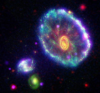 A multitelescope view of the Cartwheel Galaxy and two smaller ones that (either or both) passed through Cartwheel and generated the rings of new stars; the inner part of the Cartwheel Galaxy is the yellow mass in the center.