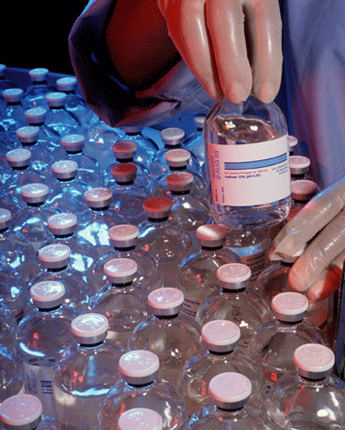 Photo of of a laboratory worker inspecting bottles of medicine.